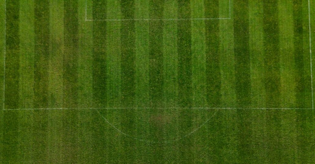 Drone shot capturing an aerial view of a well-maintained green soccer field with clear markings.