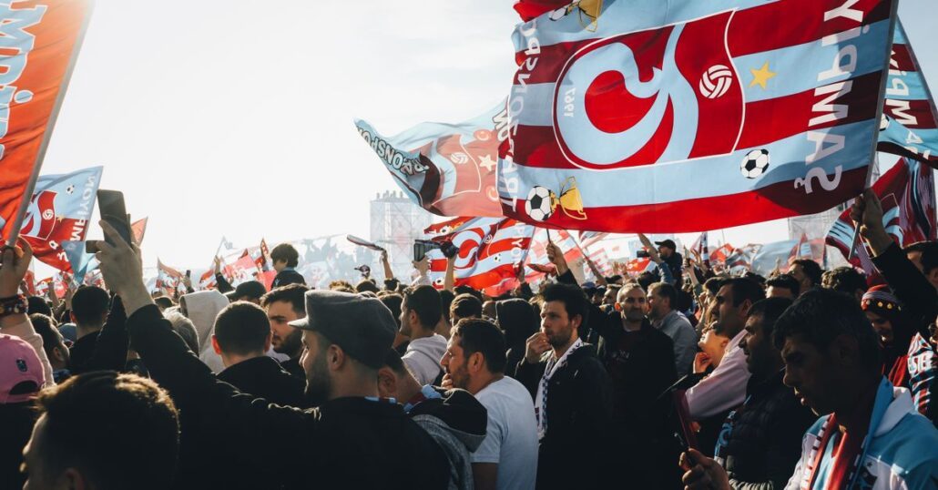 Energetic gathering with colorful flags at a lively outdoor event on a sunny day.
