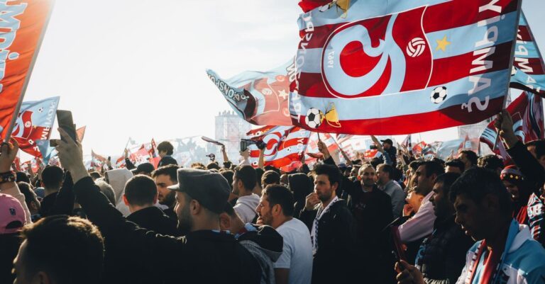 Energetic gathering with colorful flags at a lively outdoor event on a sunny day.