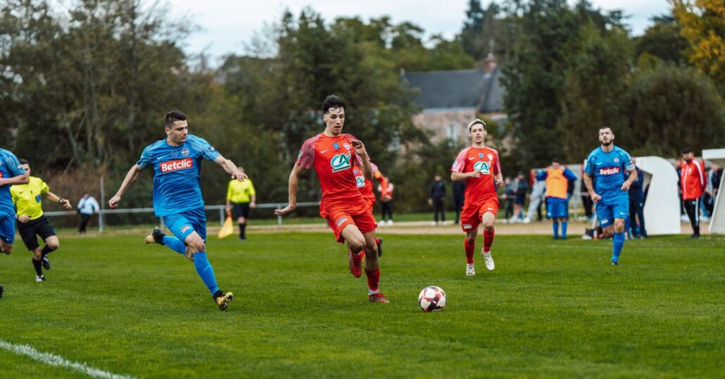 Dynamic football match action captured in France with players in red and blue jerseys.