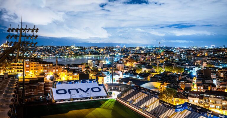 Aerial view of Istanbul's vibrant skyline at night with a focus on a well-lit stadium.