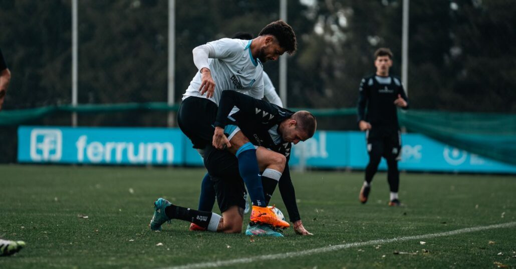 Footballers engaged in an intense match on a grassy outdoor field during the day.