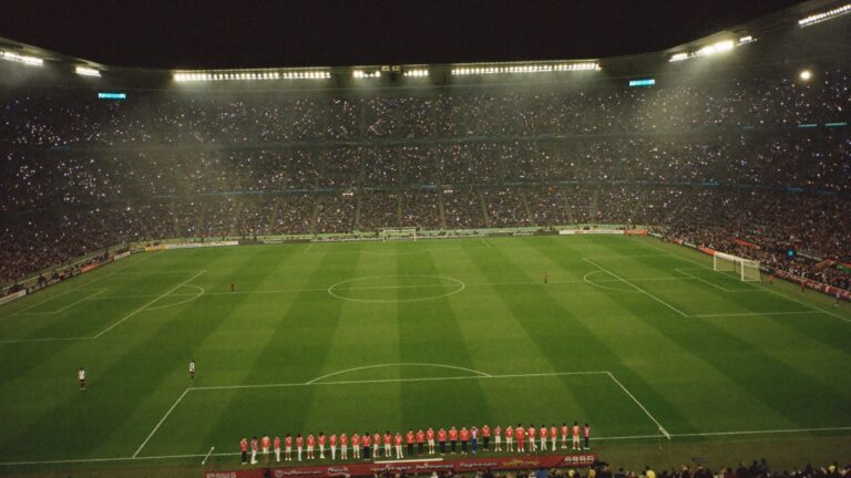 Squadre schierate a centrocampo in una notte europea, stadio pieno